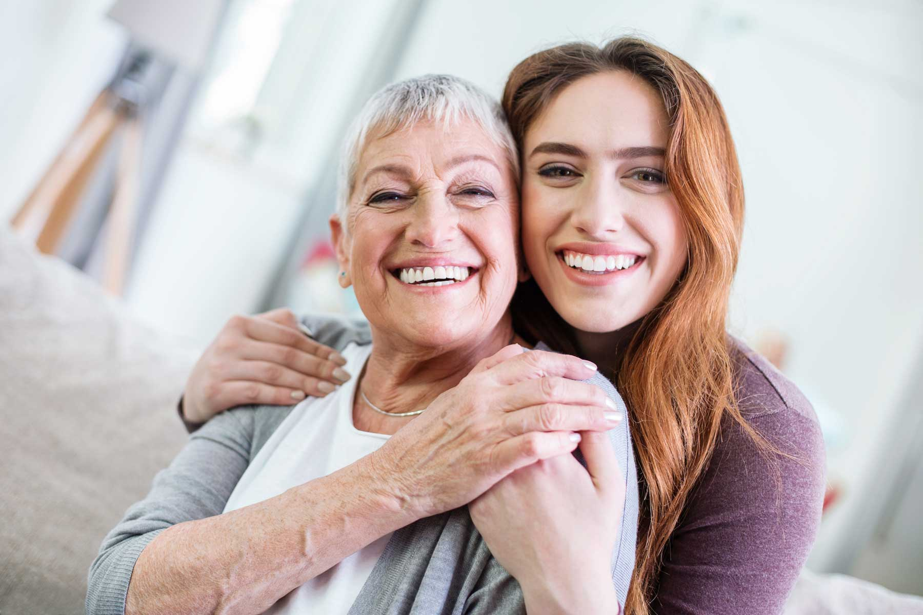 A mother and her adult daughter smiling together