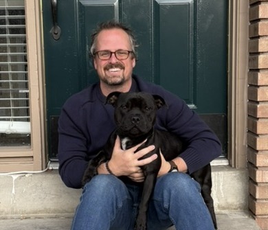 Hugh Pinnock sitting on his front steps with his dog Joey
